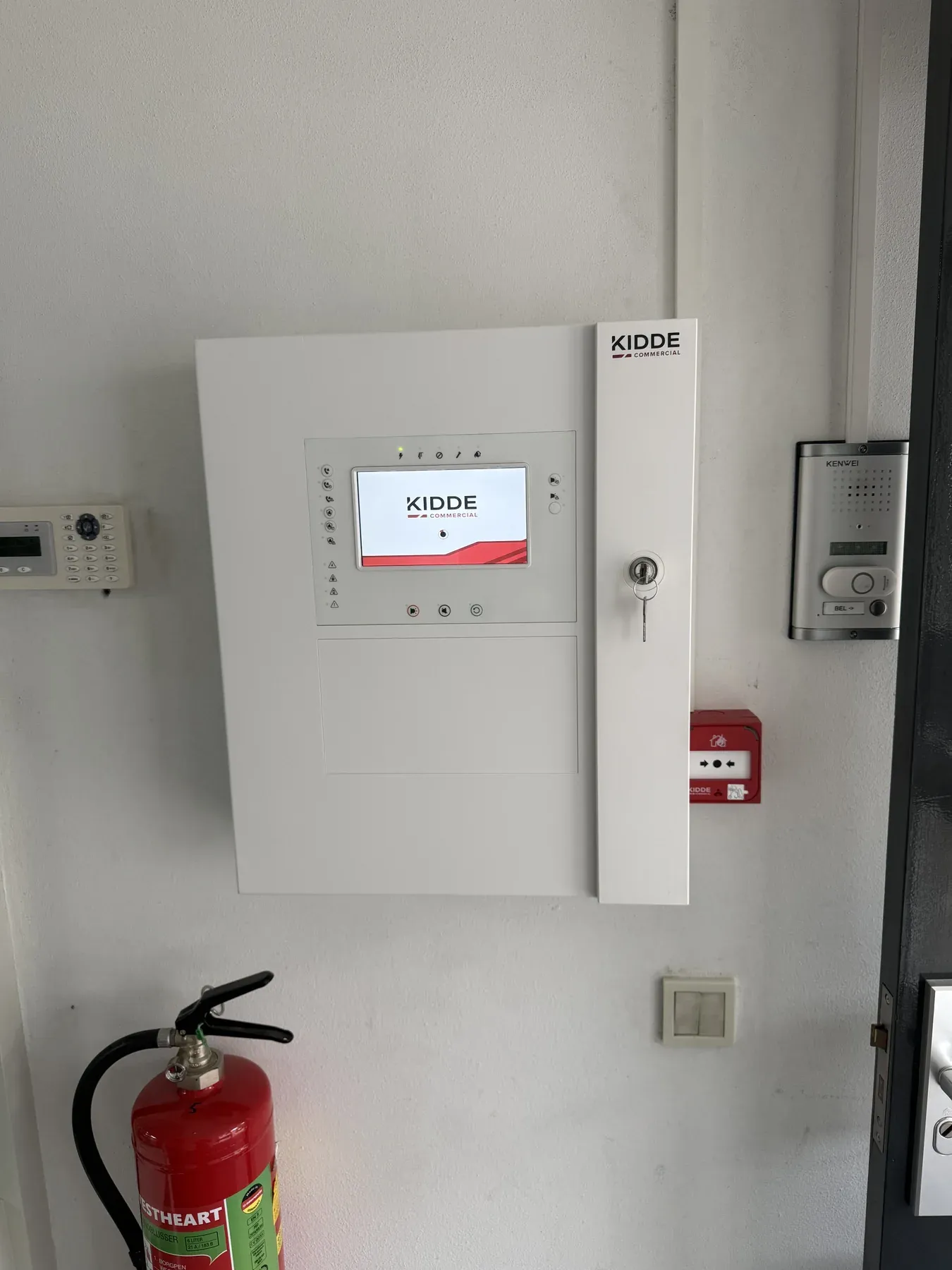 Brandmeldcentrale aan de wand naast een brandblusser