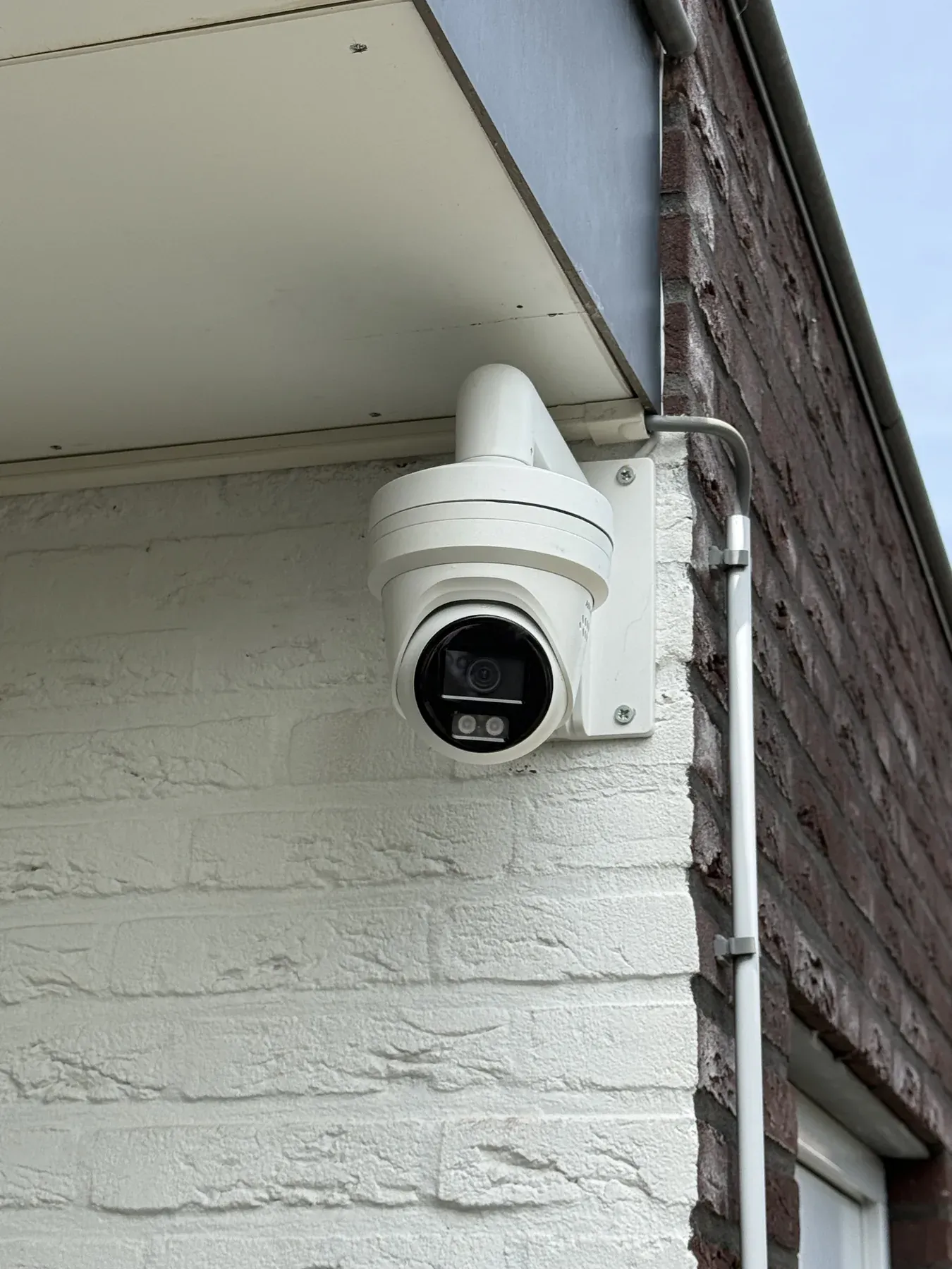 Witte turretcamera onder de dakrand van een bedrijfspand