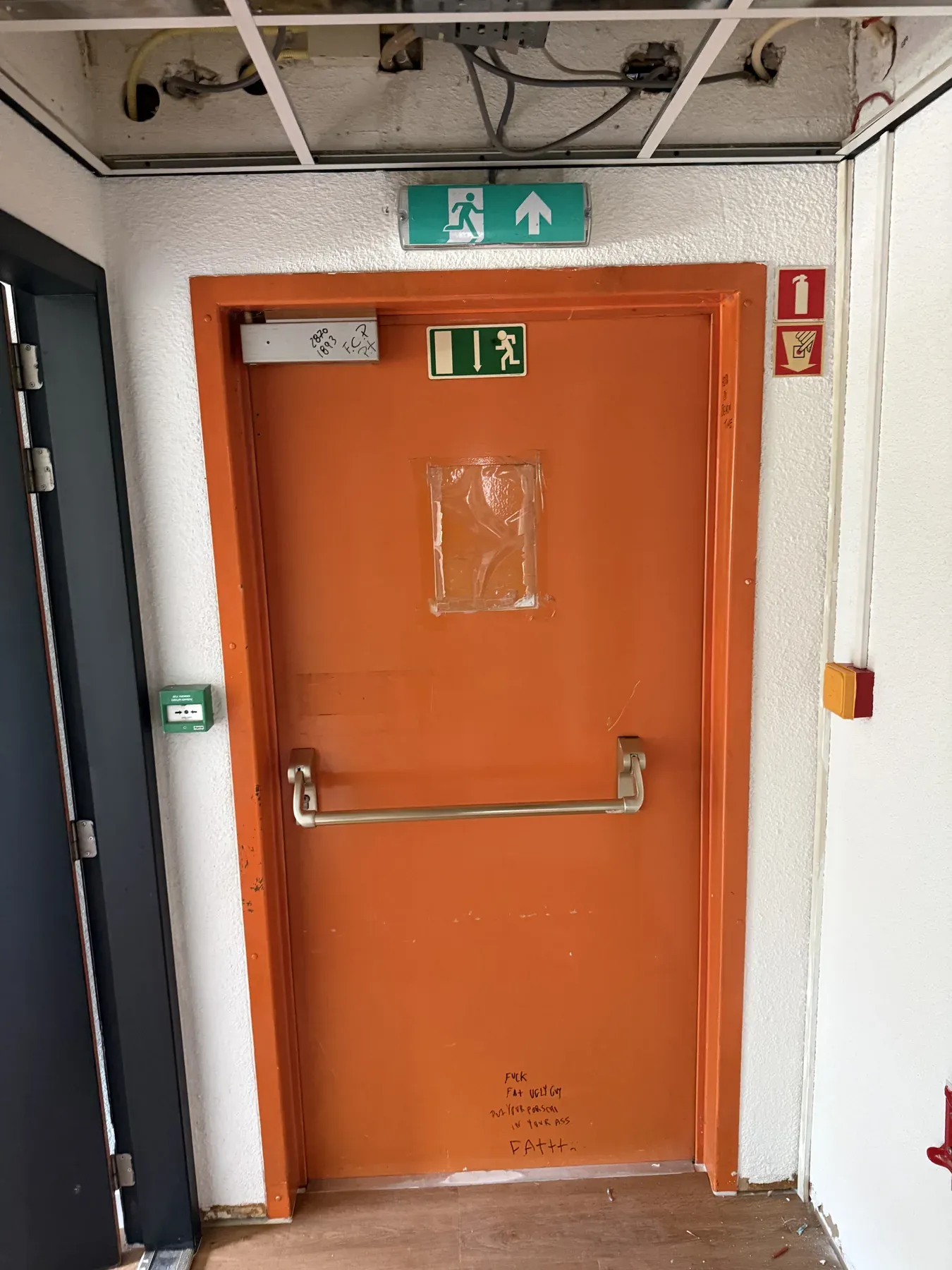 Oranje branddeur met vluchtrouteaanduiding en handbrandmelder
