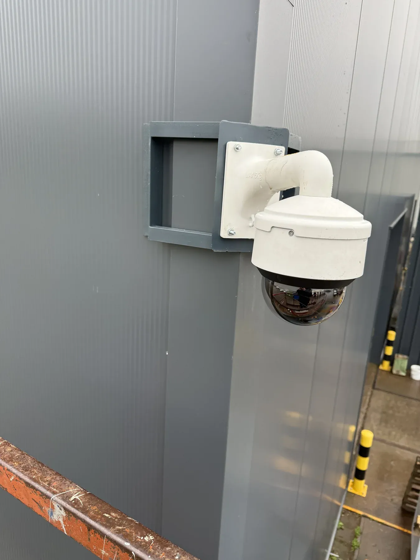 Witte PTZ-camera in een beugel aan de gevel van een bedrijfshal